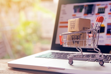 Shopping online concept - Parcel in a shopping cart on a laptop keyboard.