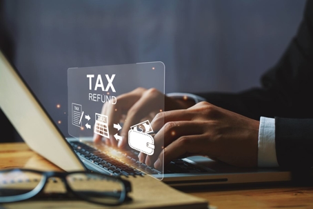 Businessman hand using a laptop with bar TAX REFUND and refund tax of duty taxation business